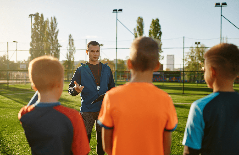 young-soccer-coach-teaching-kids-on-football-field-2023-01-07-02-18-57-utc
